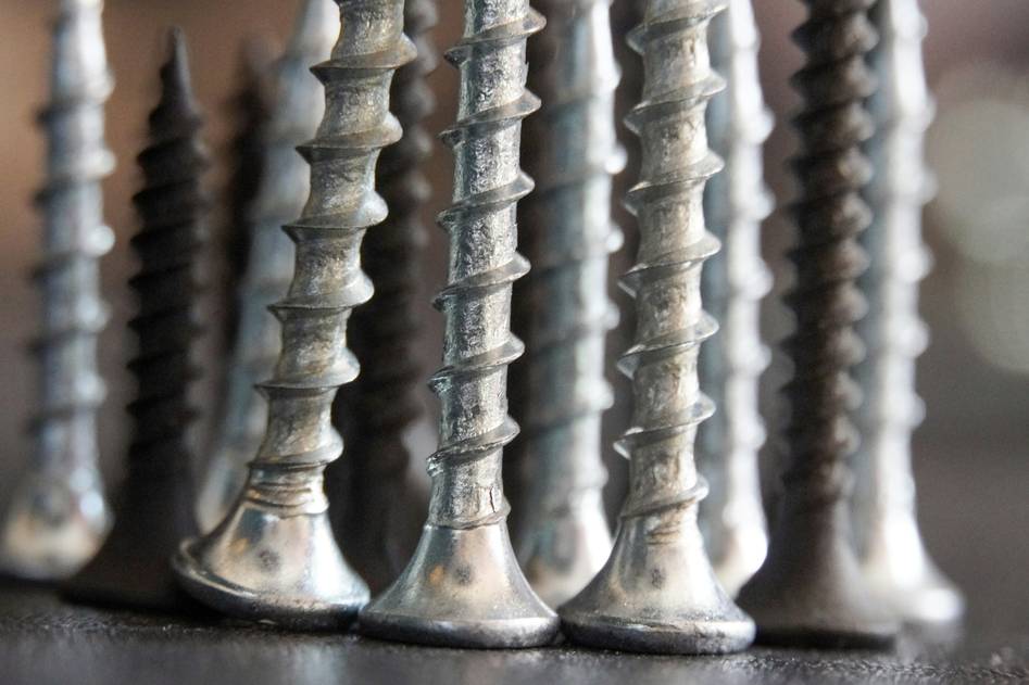 Assorted metal screws on wooden workbench with tools