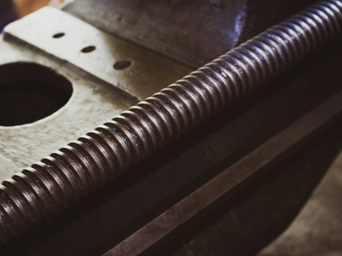 Close-up of an easy out for screws being inserted into a pilot hole in a wooden surface